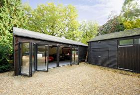 4 part bi - folding door system in black grey blends in perfectly with the woodland setting whilst demonstrating a perfect alternative use of the product